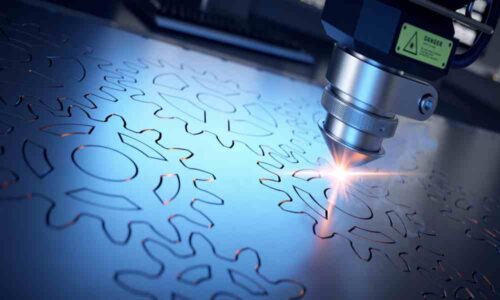 A close-up shot of a laser cutter making metal sheet gear designs for mechanical applications or purposes.