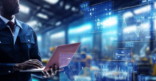 A man in a hardhat looking upward while holding a laptop. There are many graphics in the air showing various data graphs.